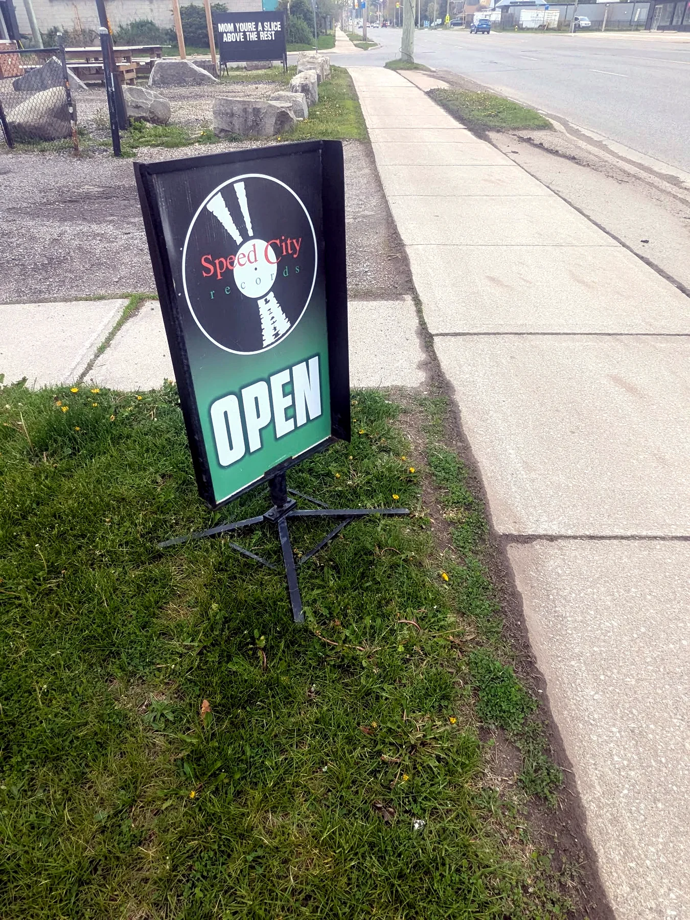 Speed City Records open sign on Springbank Drive sidewalk